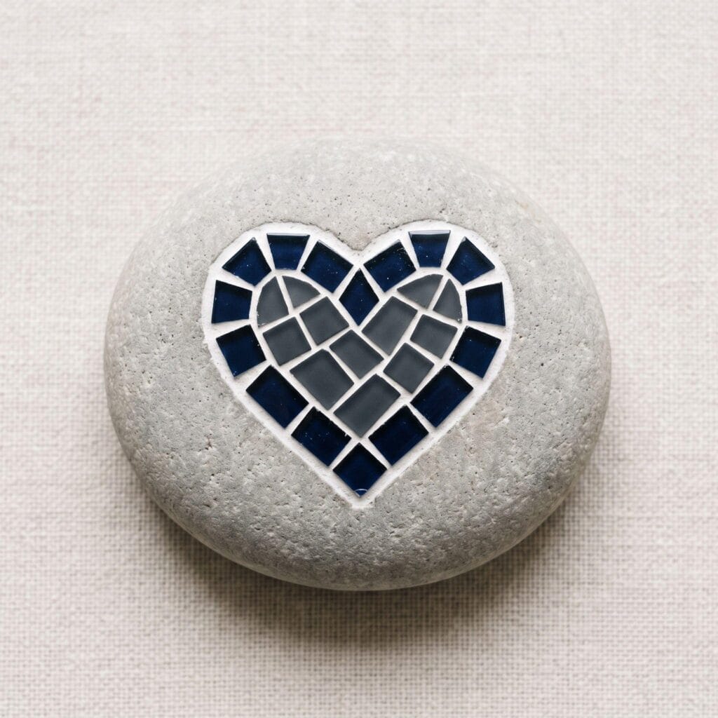 A custom mosaic garden stone featuring a heart symbol arranged from dark contrasting tile shards.