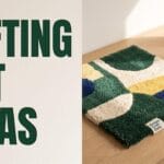 A desk showing an abstract tufted rug, a tufting gun, and bold typography reading TUFTING ART IDEAS.