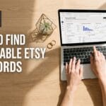 An overhead view of a woman's hands typing on a laptop on a sunny wooden desk. The laptop screen shows an Etsy 'Keyword analytics' page with performance charts. The main text on the left reads: 'HOW TO FIND PROFITABLE ETSY KEYWORDS'. A physical notebook to the right has a list of handmade jewelry and decor-related keywords.