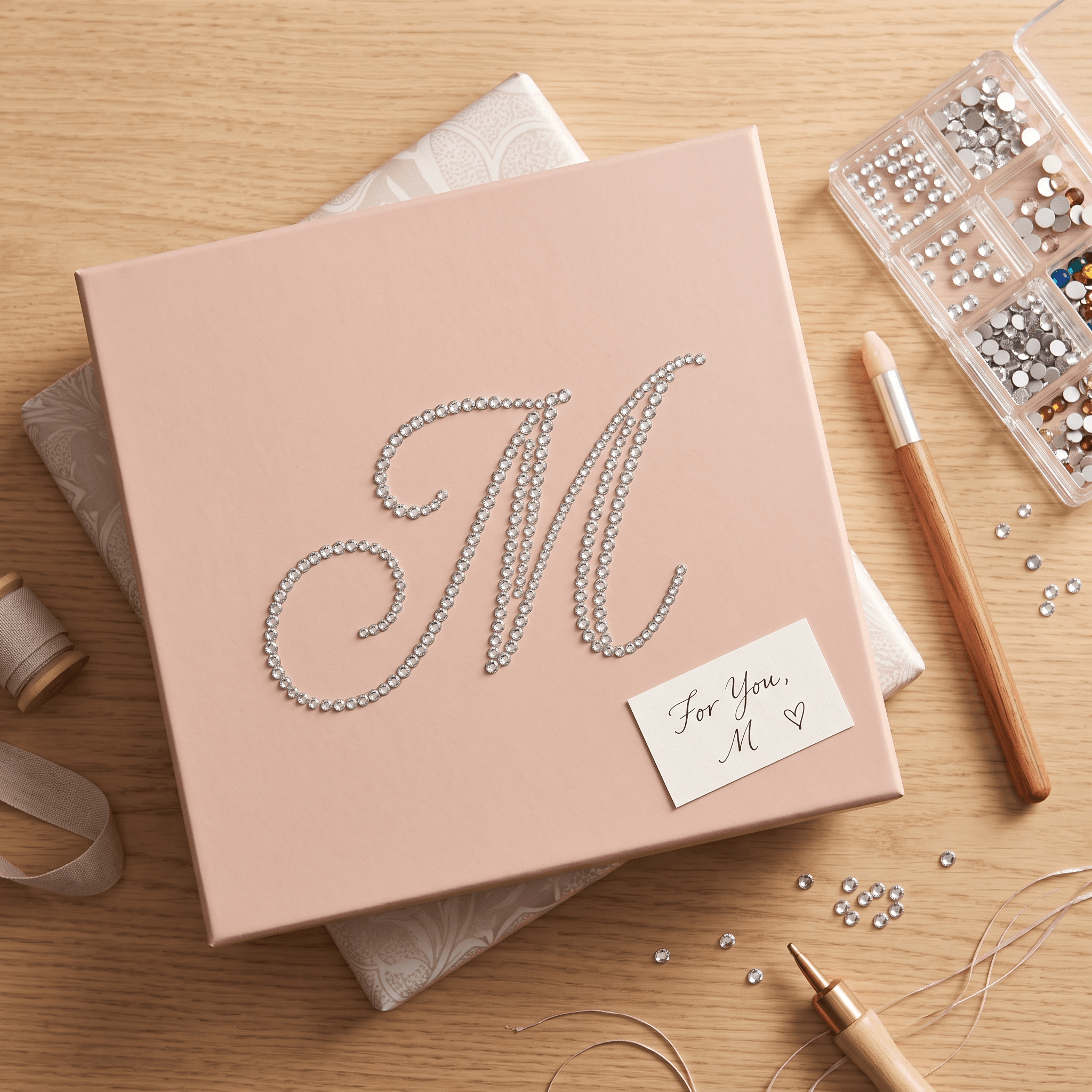 Blush pink gift box decorated with a rhinestone monogram letter M.